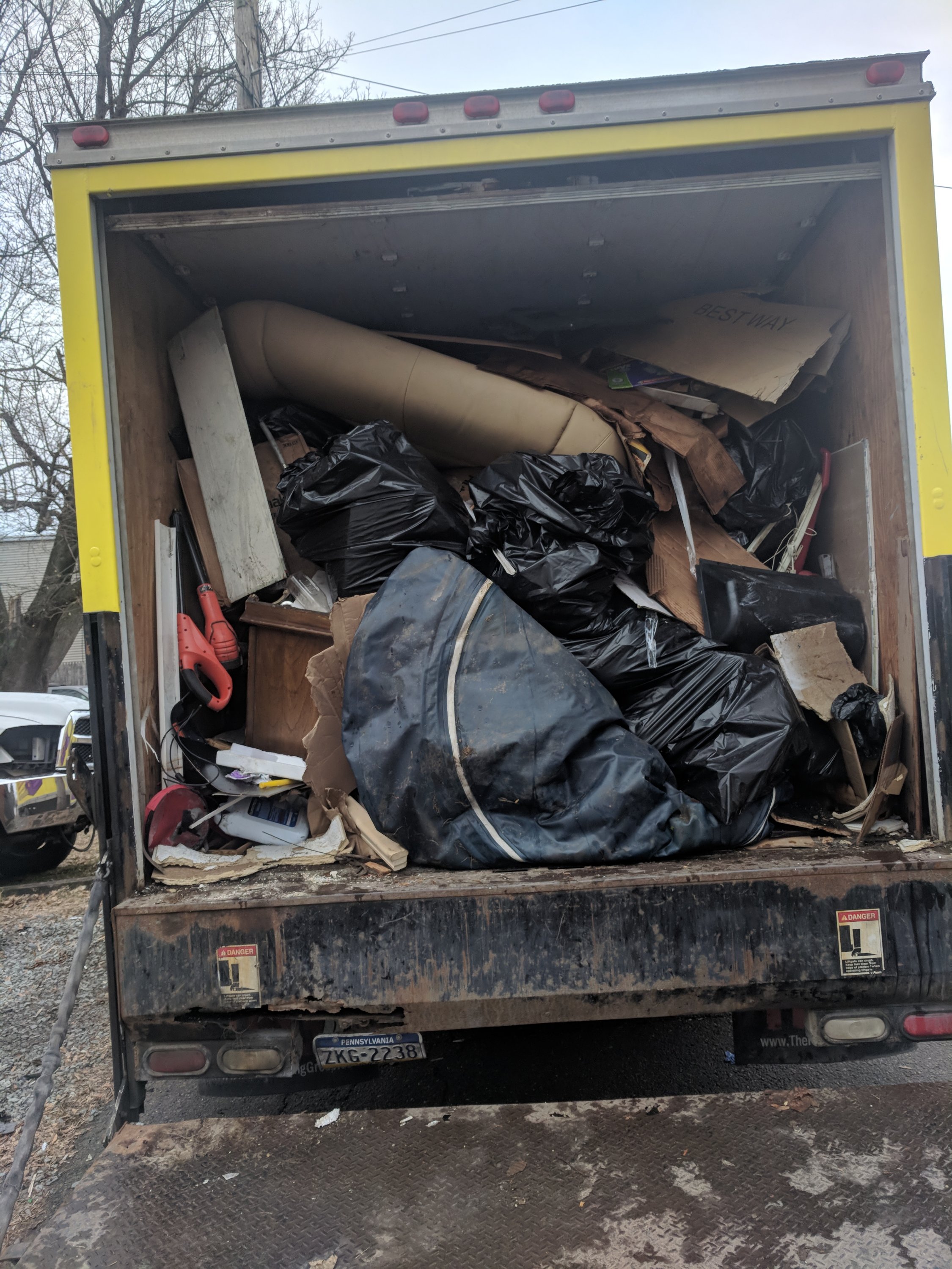 A truck loaded with assorted items, including large black garbage bags, cardboard, and various bulky materials.