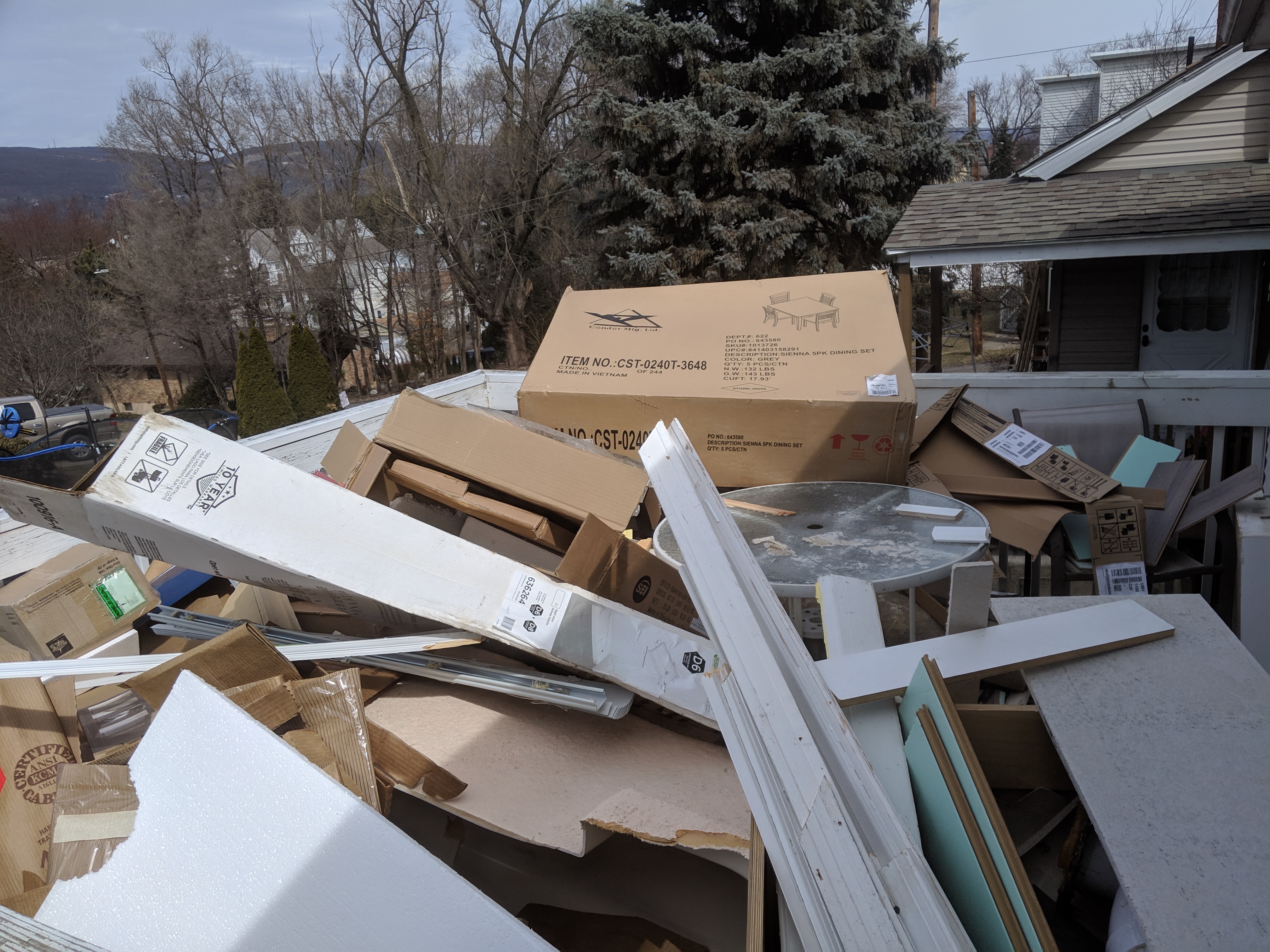 A large pile of cardboard boxes and wooden planks on a residential rooftop deck.