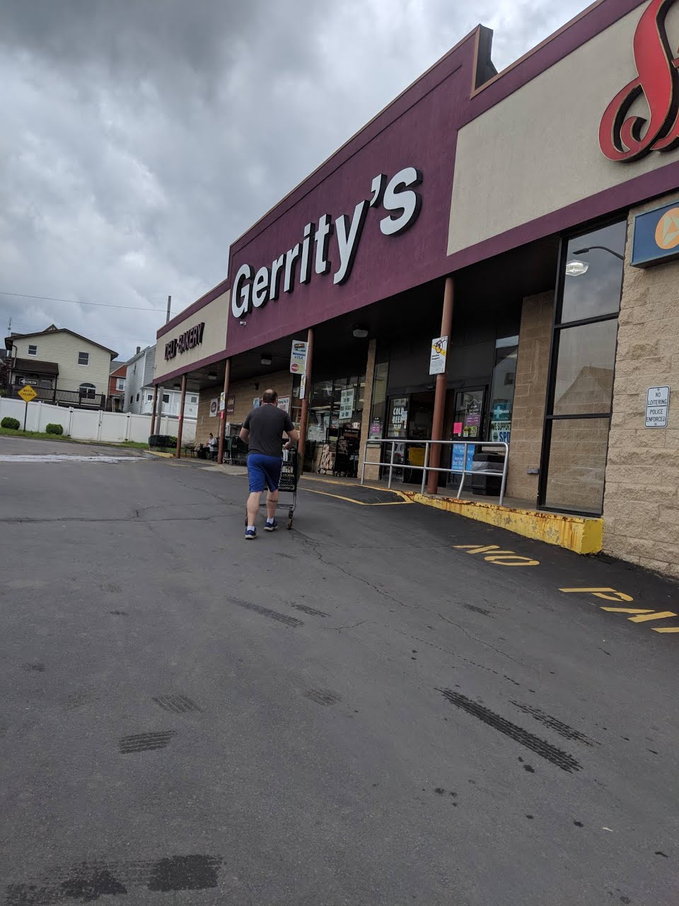 A person pushing a cart approaches the entrance of a Gerrity's supermarket under a cloudy sky.