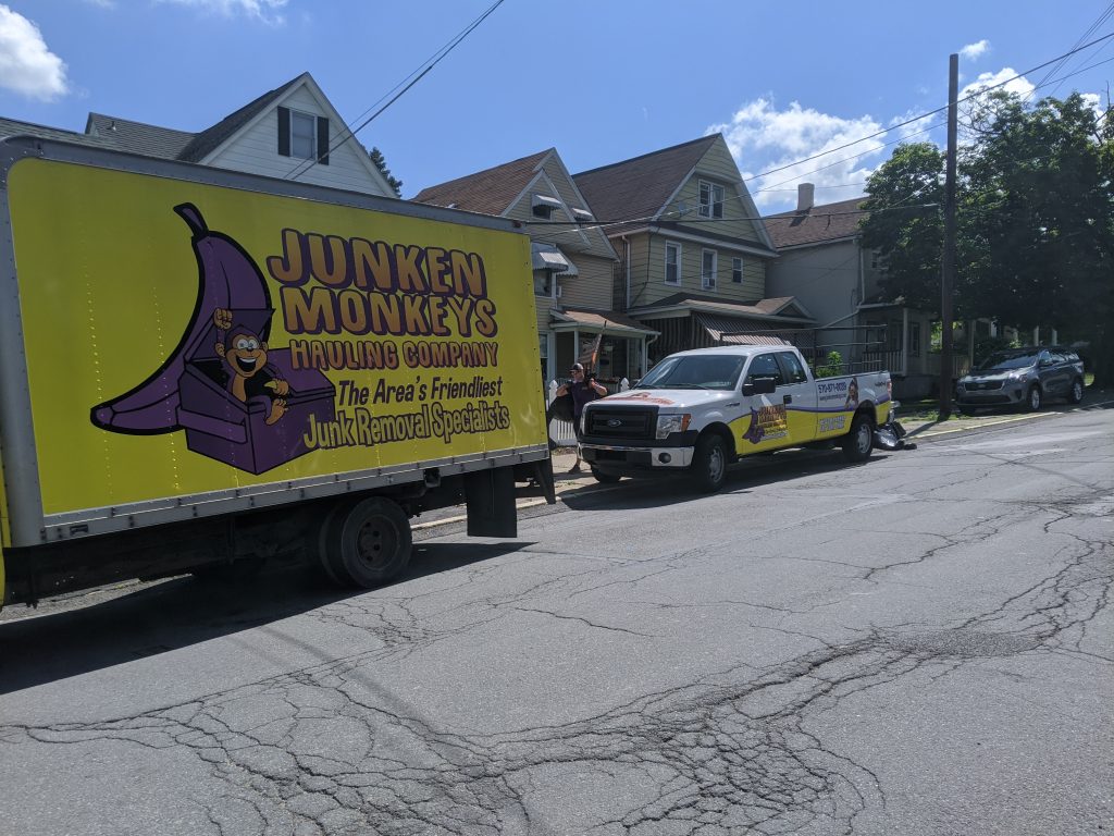 Two trucks labeled "Junken Monkeys" parked on a residential street with houses in the background.